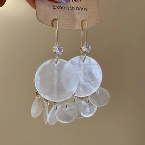 Detail of tassel earrings with shimmering mother of pearl discs and golden zircon hook