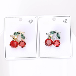 Detail of red crystal cherry and pearl bee brooches on fashion jewelry cards