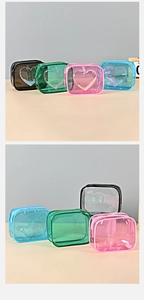 Close-up of four colorful transparent PVC makeup bags with glitter heart designs