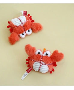 Macro detail of plush crab catnip toy with red rope wrap and soft orange faux fur