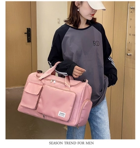 Pink waterproof fitness travel bag with multiple pockets carried by model in hallway