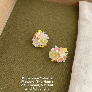 Macro shot of colorful beaded flower earrings with silver needles on green fabric