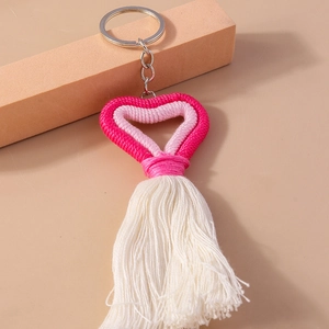 Detail of pink and white hand-woven cotton heart keychain with tassel and silver metal ring