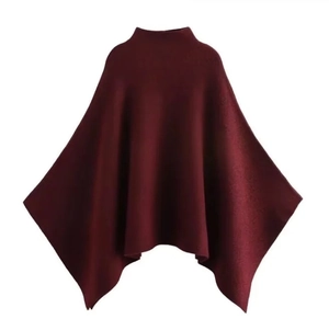 Detail of burgundy knit cape featuring premium asymmetrical stitching and textured fabric