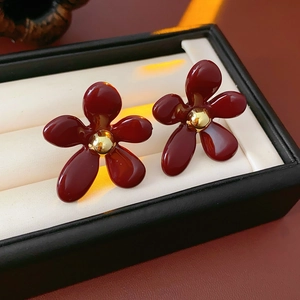 Detail of vintage red flower earrings with gold center on a jewelry display cushion