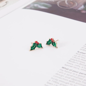 Macro detail of holly leaf Christmas studs with red berries on a gold metal base