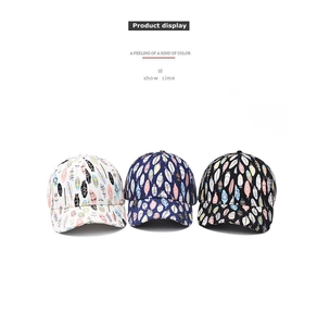 Detailed view of three cotton baseball caps with colorful feather prints in white, navy and black