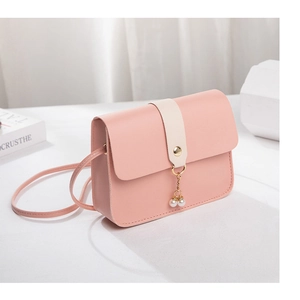 Detail of pink mini crossbody bag featuring a white buckle and elegant pearl pendant