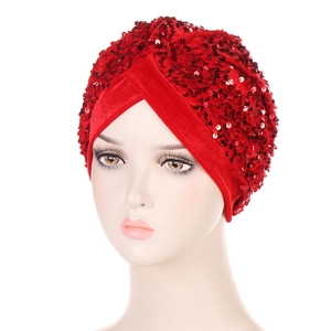 Close-up of red velvet turban hat featuring shimmering sequins and pleated cross design