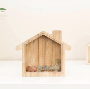 Detail of wooden house-shaped piggy bank with transparent panel showing coins inside