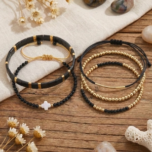 Böhmisches Armbandset in Schwarz und Gold mit Kreuzanhänger auf rustikalem Holzhintergrund