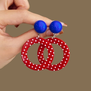 Close-up of resin drop earrings with blue studs and red polka dot ring pendants