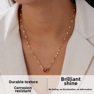 Close-up of gold plated stainless steel chain with red heart pendant on female model