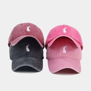 Detail view of four washed cotton baseball caps with embroidered rabbit logos in various colors