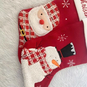 Detail of red knitted Christmas stockings with Santa Claus and Snowman on white fur