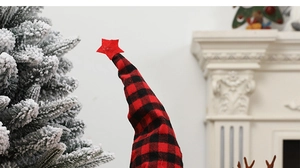 Detail of red and black plaid Christmas gnome hat with star topper and fabric texture