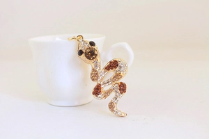 Detail of a golden snake keychain pendant with sparkling white and brown rhinestones