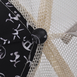Detail of baseball cap showing black floral print fabric and beige mesh texture