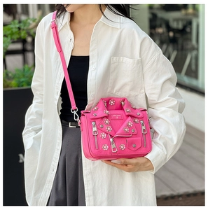 Detail of fuchsia jacket-shaped crossbody bag with floral rivets and zippers