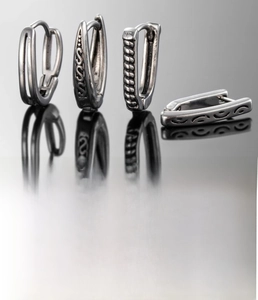 Macro detail of silver titanium steel men's earrings with retro textured patterns