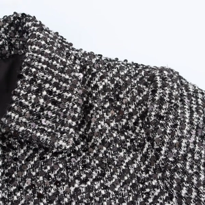 Macro shot of black and white tweed fabric with shimmering sequin embellishments