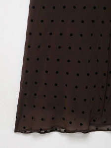 Detailed close-up of brown sheer mesh fabric with black polka dots and hemline texture
