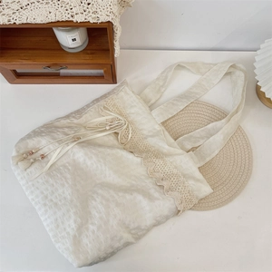 Detail of off-white canvas tote with wavy lace trim and elegant beaded tassel accents