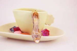 Close-up of sparkling crystal stiletto high heel keychain hanging on a tea cup edge