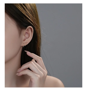 Detailed view of minimalist S999 sterling silver hoop earrings worn on earlobe and cartilage