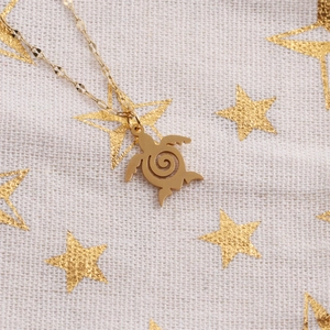 Detailed close-up of a golden turtle pendant necklace on a decorative starry fabric background