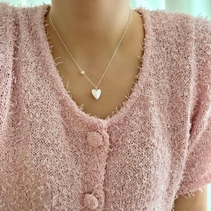 Detail of silver heart necklace with pearl accent worn on neck for elegant jewelry style