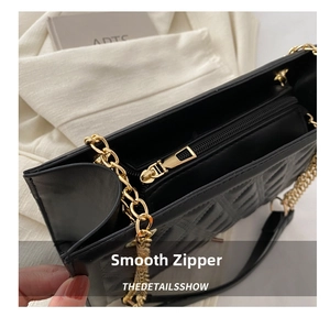 Close-up of smooth metal zipper and gold chain detail on black quilted tote bag