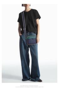 Détail du sac bandoulière en cuir bicolore avec rabat vert et corps bleu sur modèle