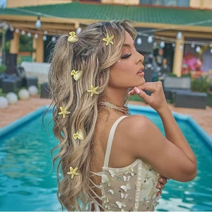 Close-up of golden shell and starfish hair clips worn by a model at a sunny poolside