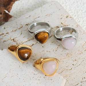 Tiger eye and rose quartz rings in gold and silver finish on natural stone background