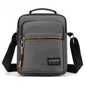 Close-up of waterproof grey sports crossbody bag with fashion label and orange puller