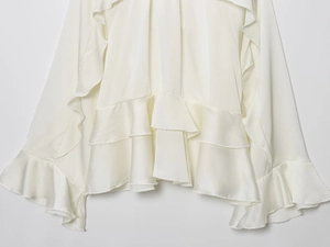 Detail of elegant tiered ruffle hem and cuffs on a white chiffon layered shirt blouse