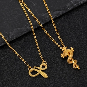 Detailed shot of golden snake and caduceus pendants on a dark textured surface