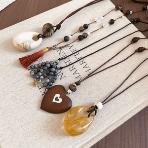 Vintage stone beaded necklaces with heart tassels and resin drops on an open book