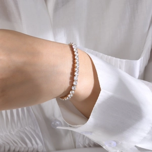 Close-up of sparkling gold tennis bracelet with clear zircon stones on woman wrist