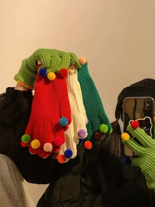 Dettaglio dei guanti in maglia con pompon colorati in verde, rosso e bianco per l'inverno