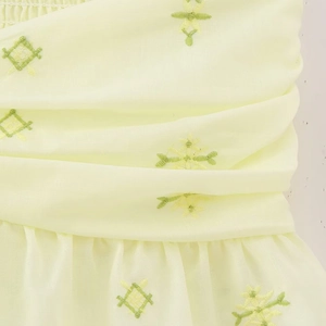 Haut court bustier jaune clair avec broderie verte et détails de volants plissés