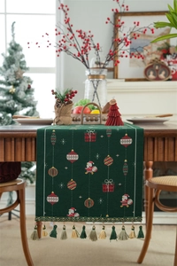 Close-up of green Christmas table runner with festive jacquard patterns and colorful tassels