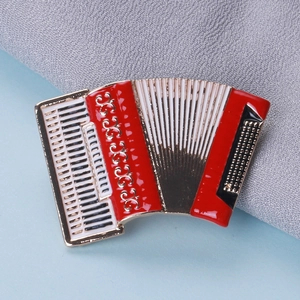 Close-up of accordion brooch with red and black enamel detail on golden metal edge