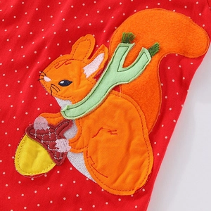 Detail of cartoon squirrel embroidery and polka dot fabric on red girls' sweatshirt