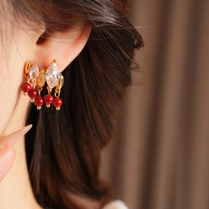 Dettaglio degli orecchini a fiore placcati oro 18K con perline rosse e cristalli zirconi