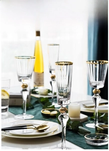 Close-up of crystal champagne glass with gold rim and decorative golden ball on the stem