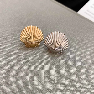 Detail of scallop shell ear cuffs in gold and silver finishes with ribbed texture