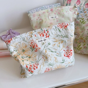 Trousses de maquillage en coton fleuri avec étiquette sur une surface blanche