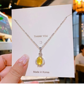 Detail of silver chain with yellow teardrop zircon pendant and Thank You card